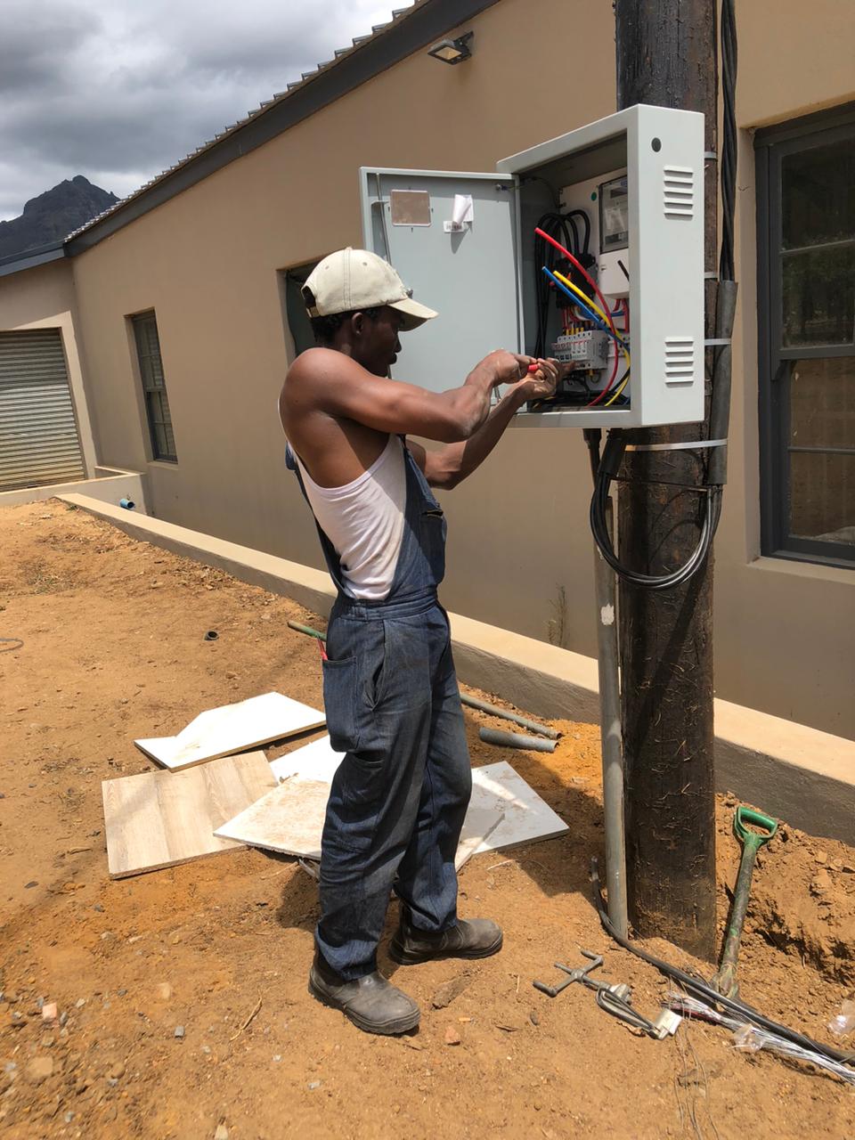 Electrician wiring an outdoor supply box at a new build